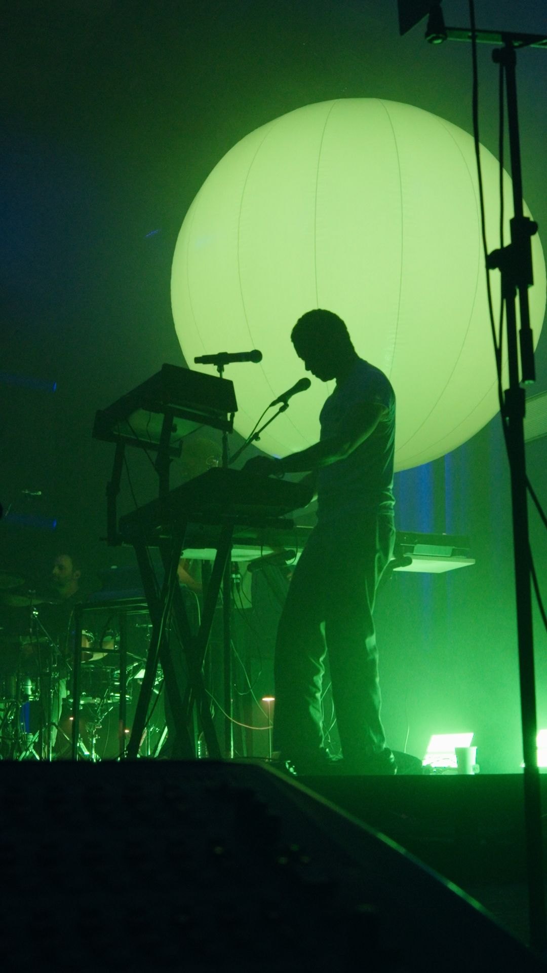 Chaz Bear silhouetted at the keys against the sphere lit green