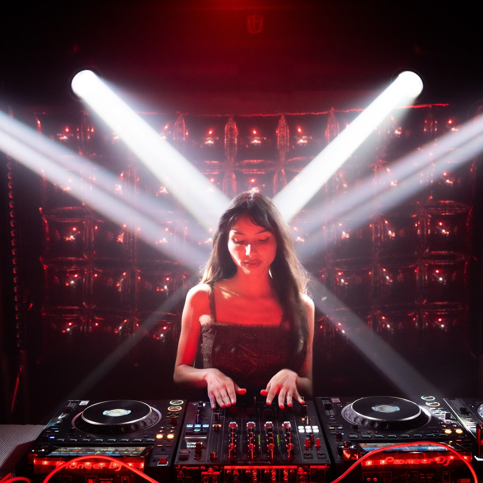BalloonBooth at Club Six — Erika at the decks with four white moving-head beams crossing above her, the mylar balloon wall lit red behind