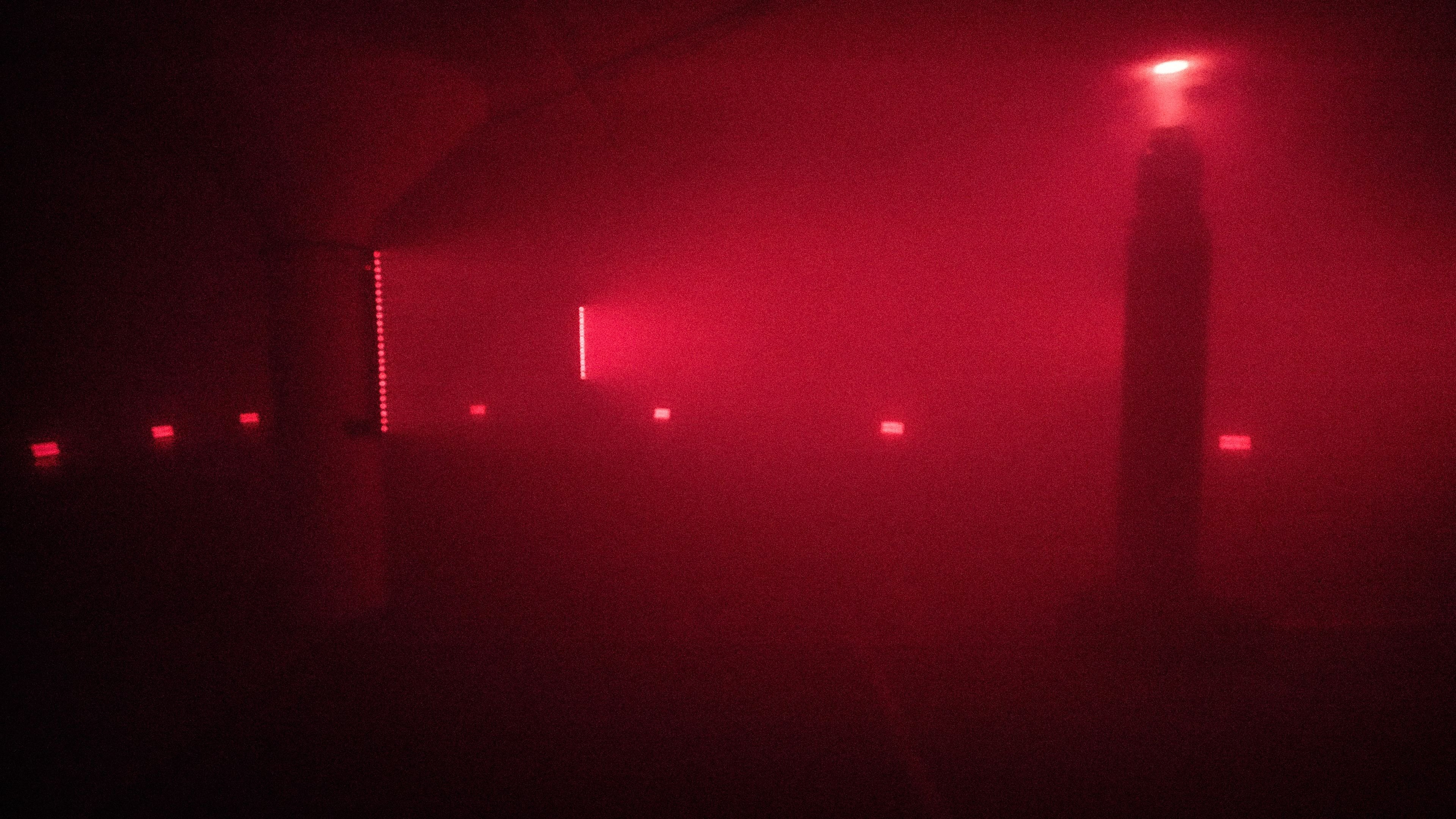 The empty garage in deep red, battery strips glowing on the columns and floor panels along the walls