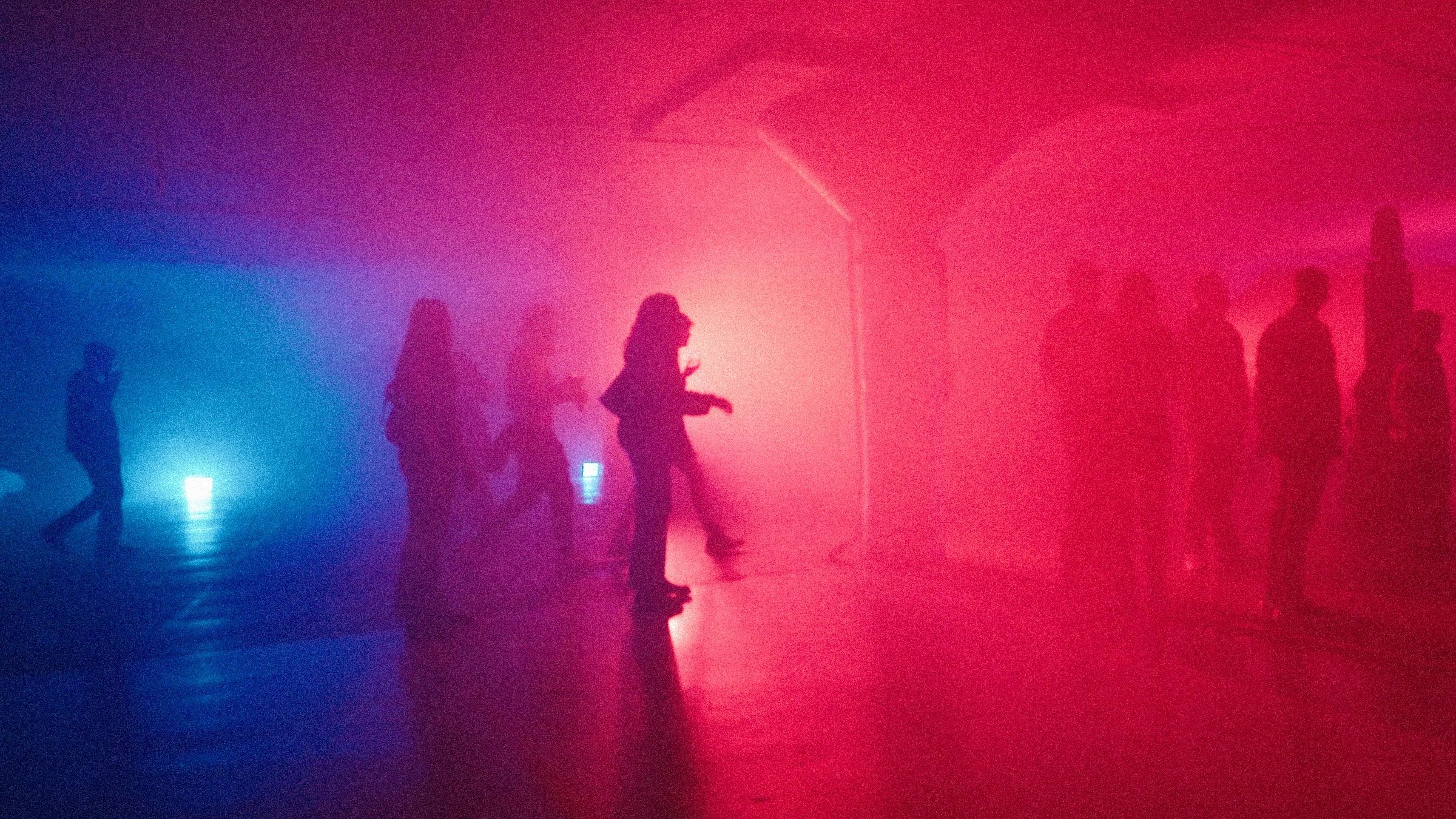 Attendees walking into the garage through pink and blue fog, silhouetted against the haze