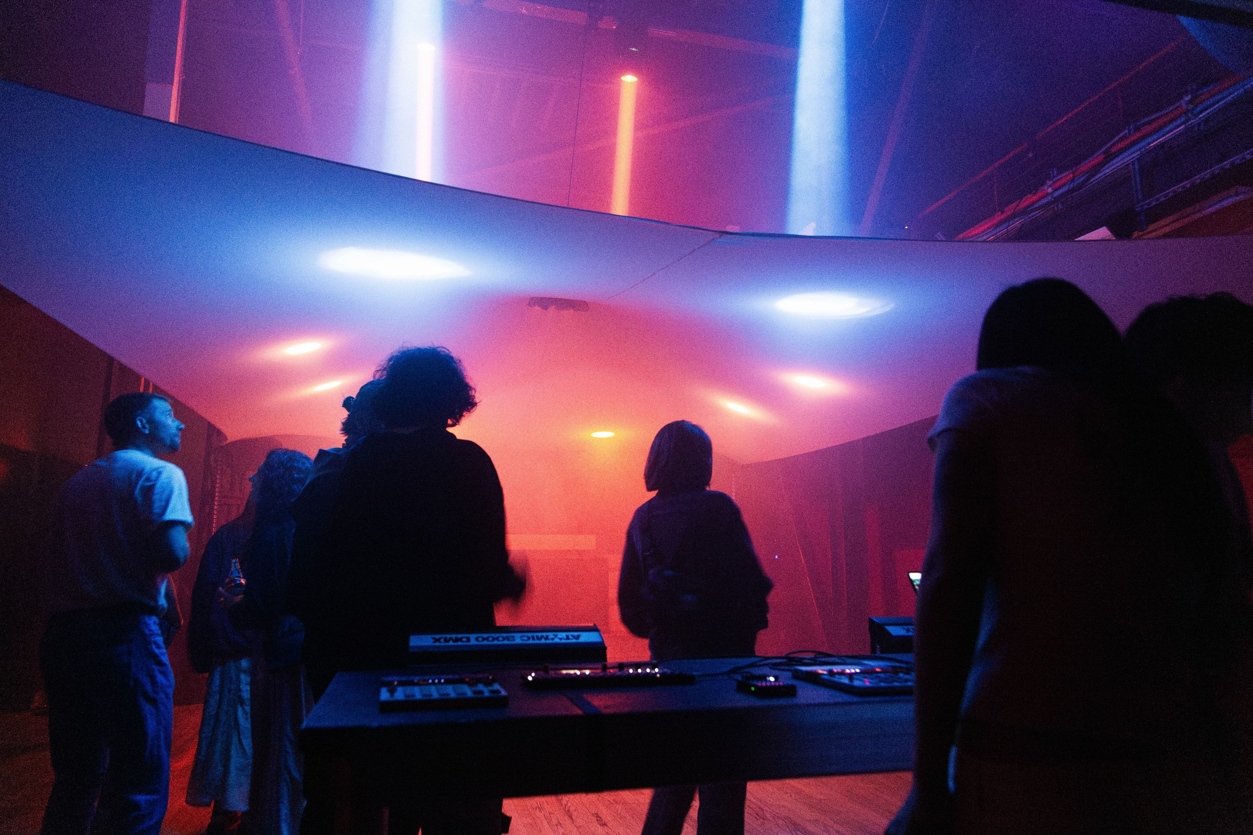 The crowd around the lighting booth, the canopy above lit blue on one side and orange on the other