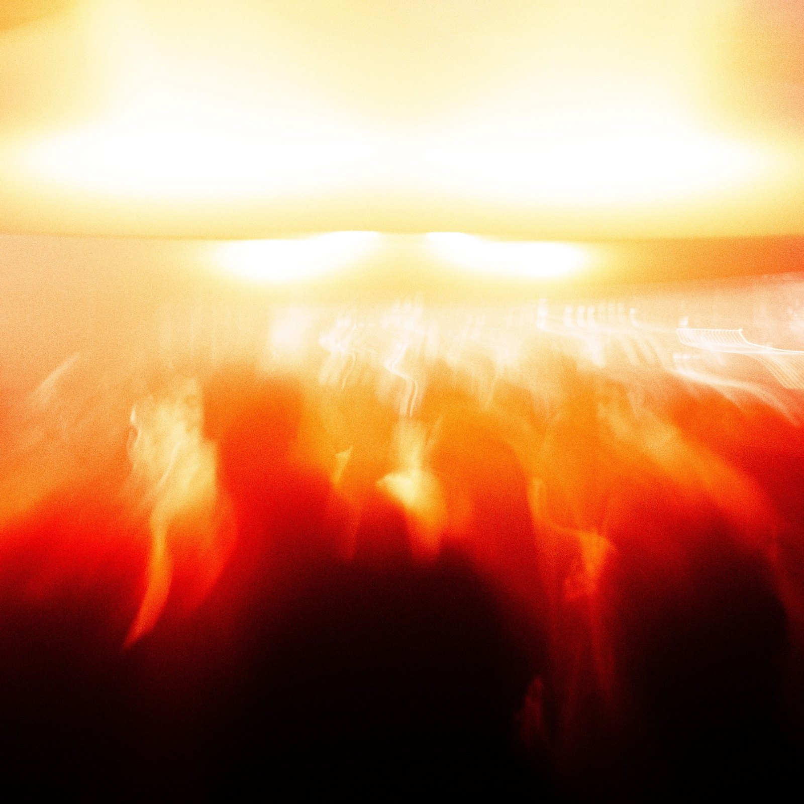 Heliotropic at Public Works — the canopy blown out to white and orange above a crowd rendered as streaks of shadow