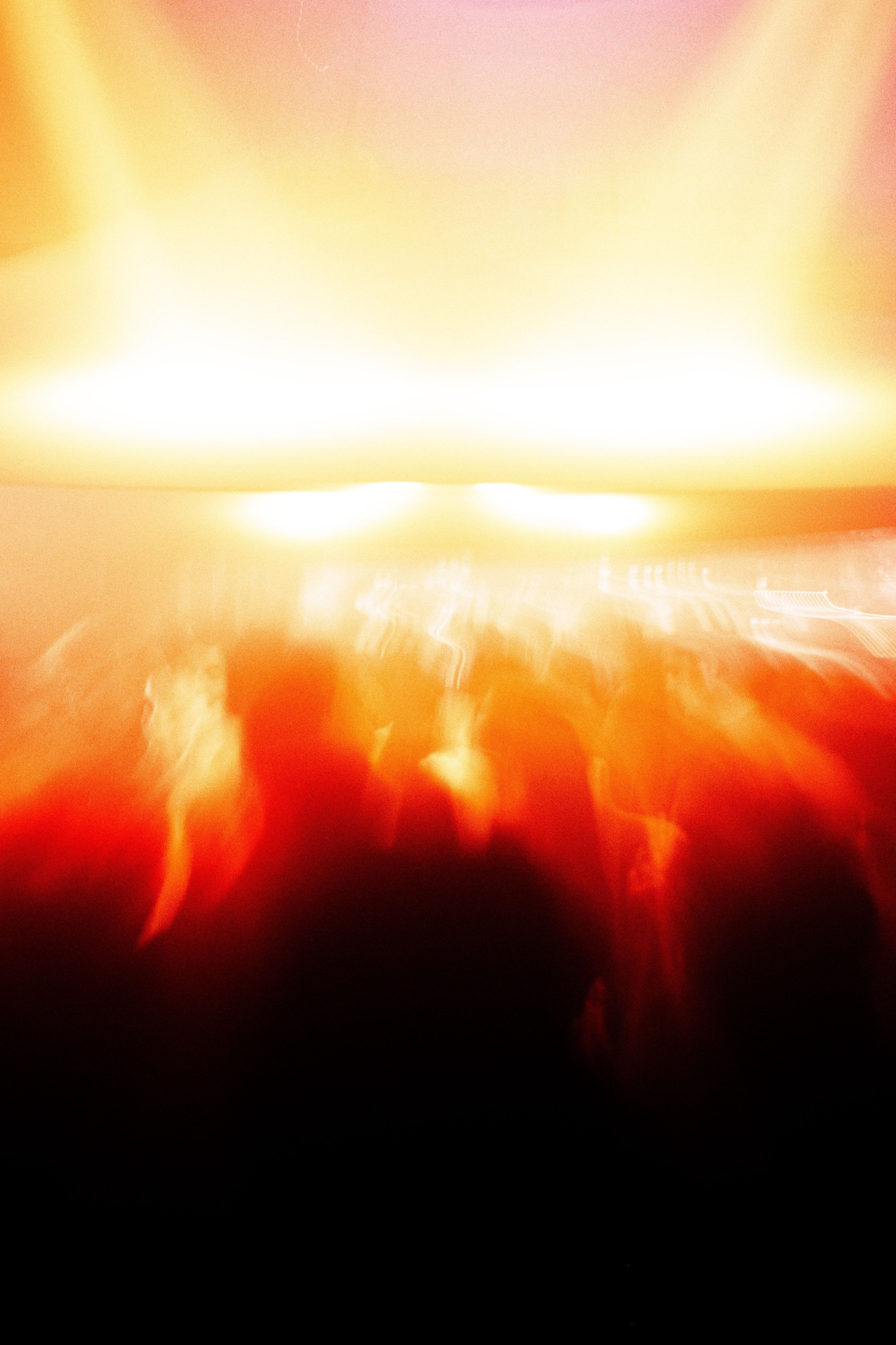 Heliotropic at Public Works — the canopy blown out to white and orange above a crowd rendered as streaks of shadow