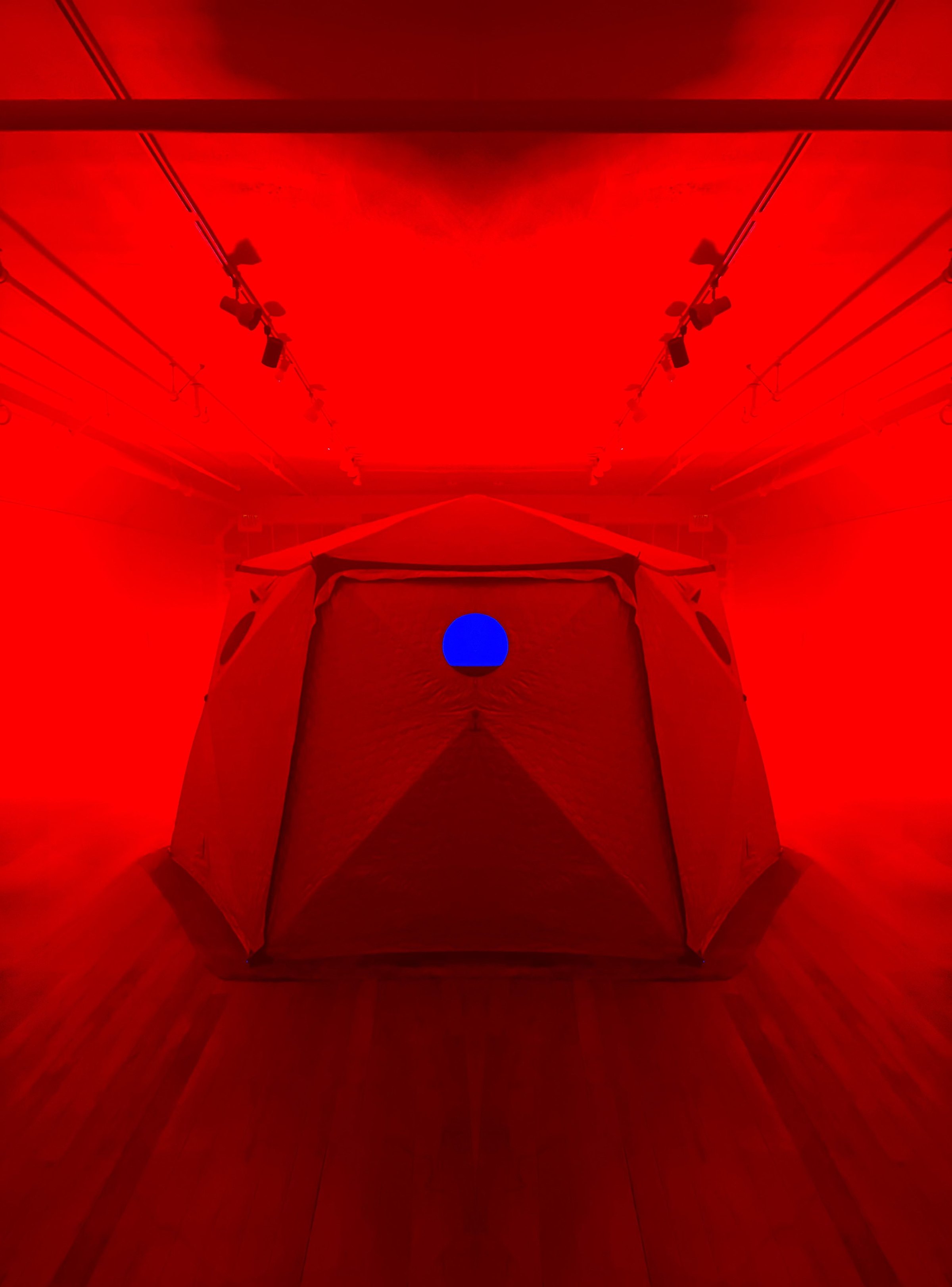 Inside HoloDome1, the Shiftpod tent lit solid red with a single blue light on its far wall