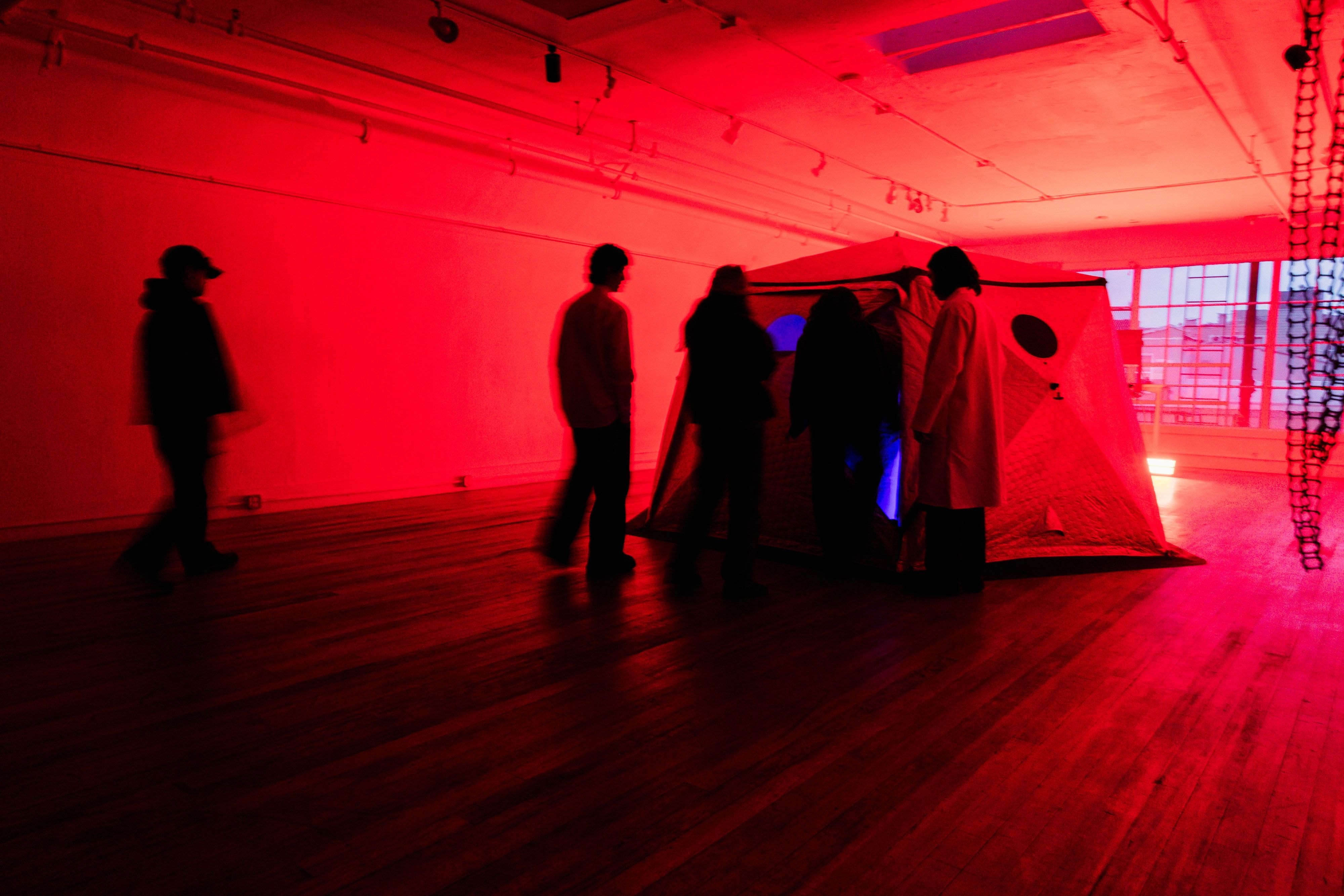 The HoloDome1 tent in the red-lit loft with guests gathered beside it